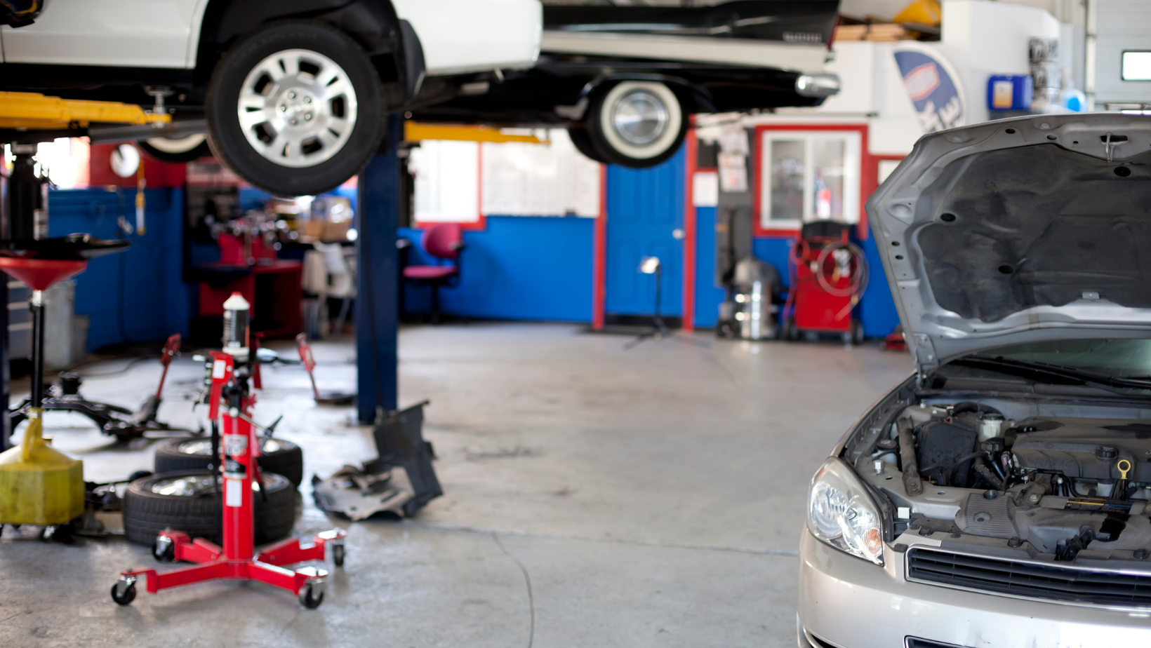 Auto repair shop with a car on a lift and another car with its hood open