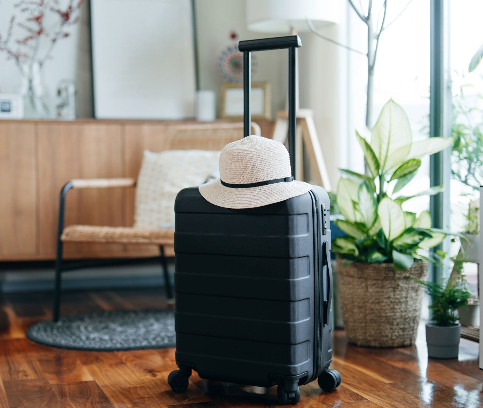 A black suitcase with a hat on top of it in a living room.