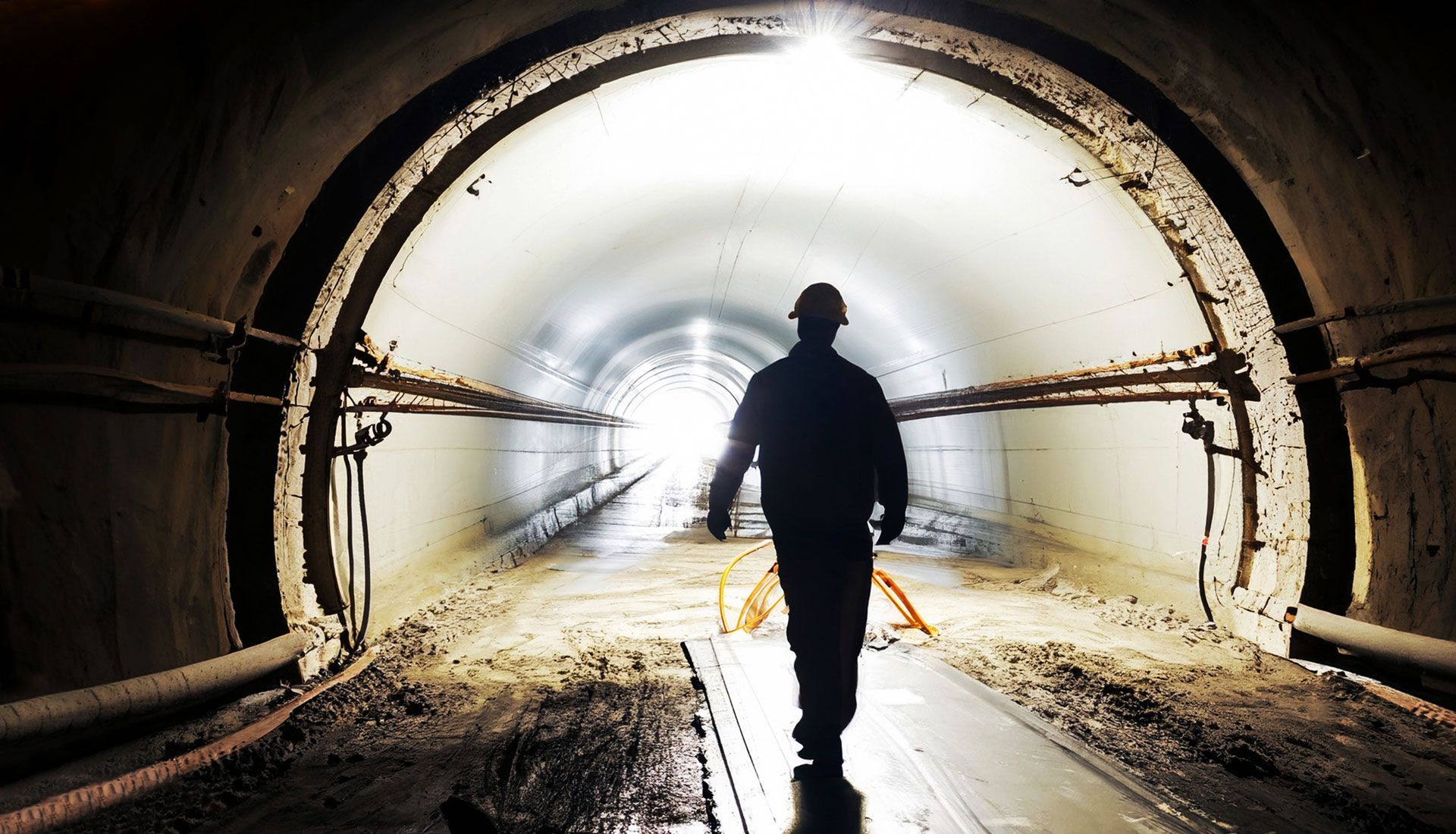 A man is walking through a tunnel with a light at the end.