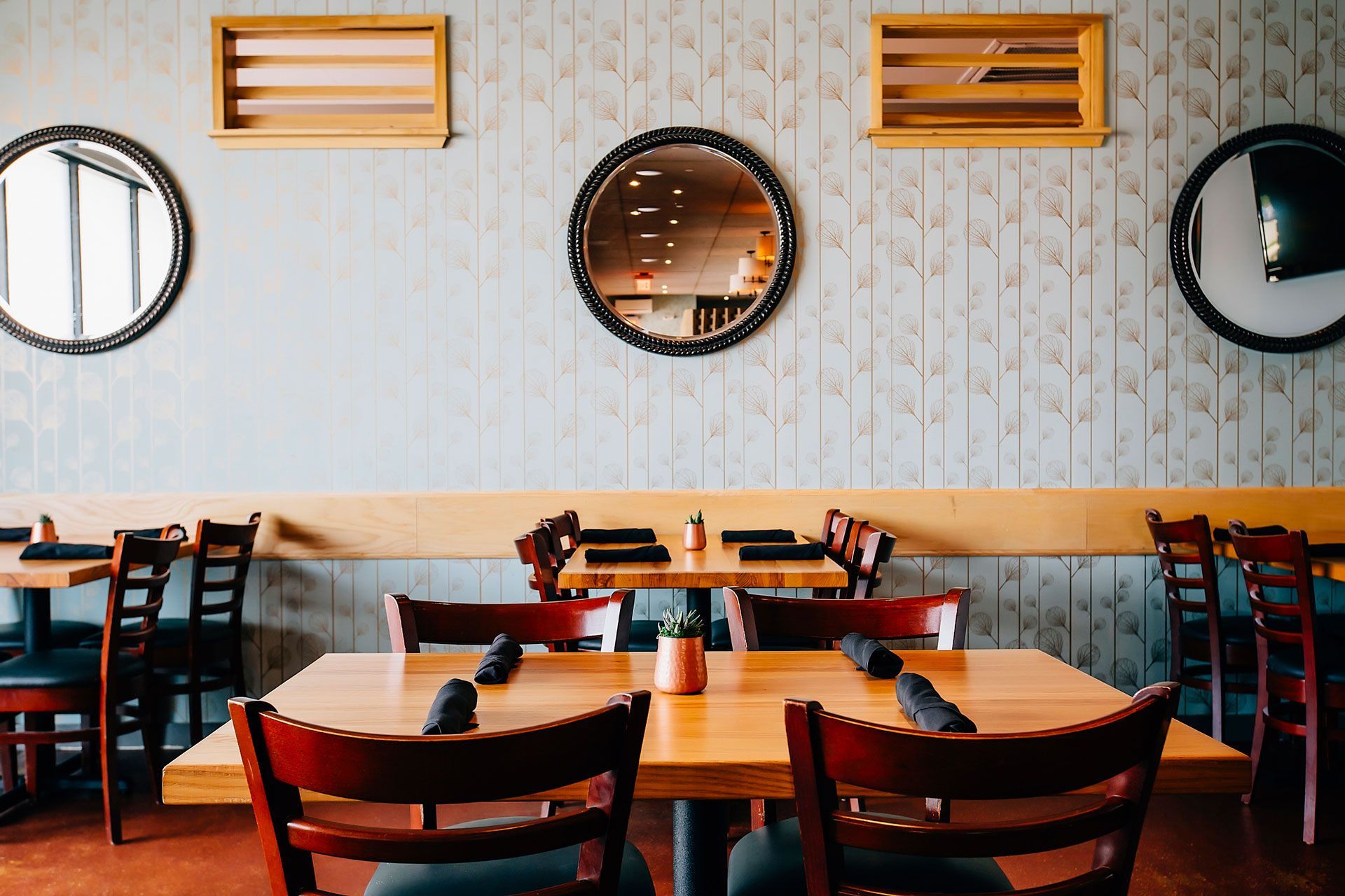 A restaurant with tables and chairs and mirrors on the wall.