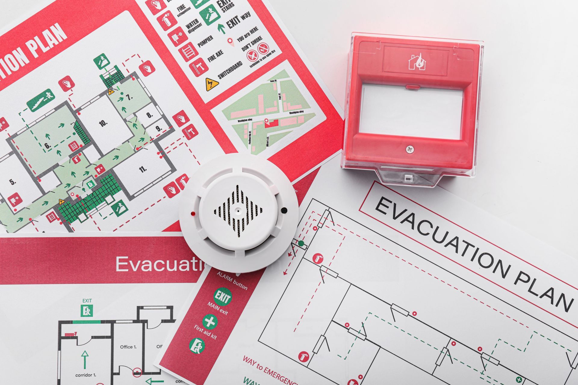Fire safety equipment: evacuation plans, smoke detector, and alarm in a red and white setting. Fire safety equipment: evacuation plans, smoke detector, and alarm in a red and white setting.