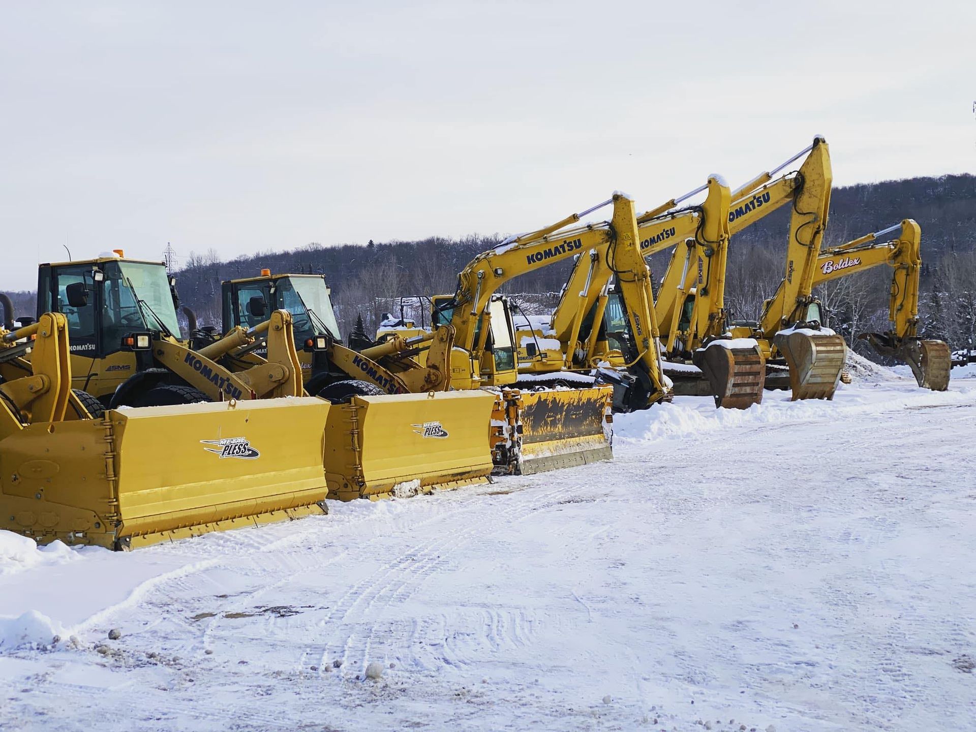 Engins de chantier jaunes stationnés sur un terrain enneigé.