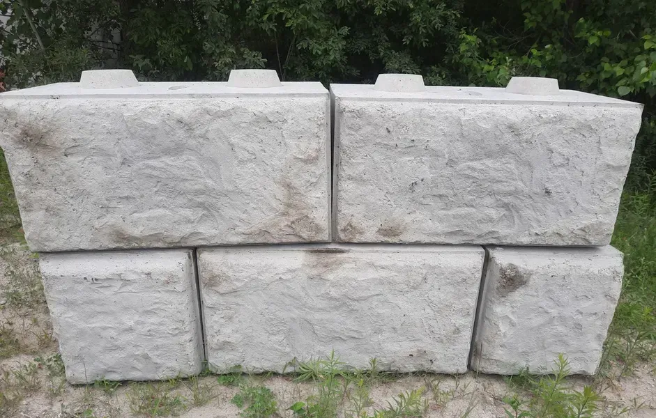 Blocs de béton gris empilés pour créer un mur de soutènement, à l'extérieur.