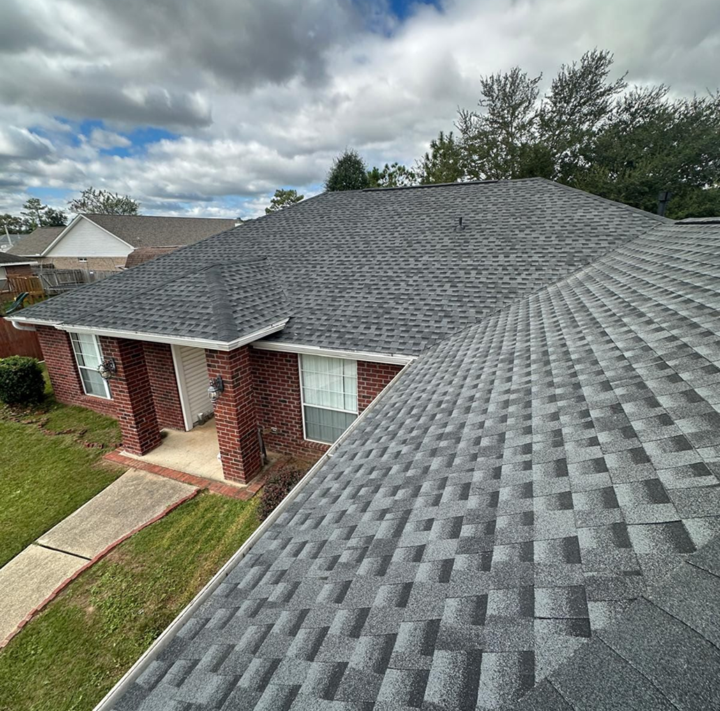 Brick house with a blue roof and a roofing company yard sign in the front lawn.