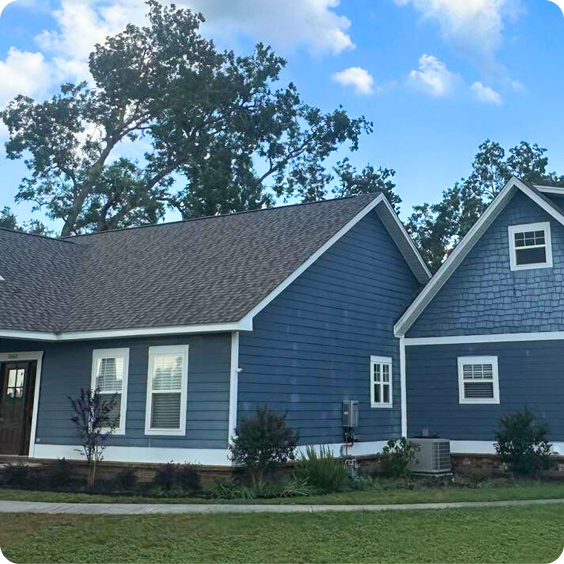 Blue suburban house with white trim and a detached garage under a partly cloudy sky