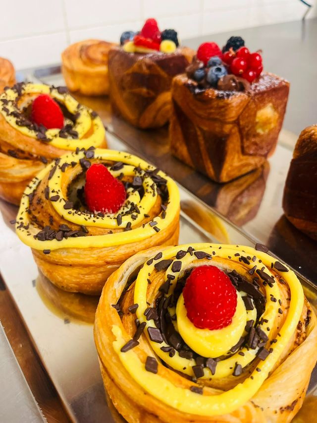 Pasticcini guarniti con fragole, mirtilli e glassa al cioccolato su un vassoio