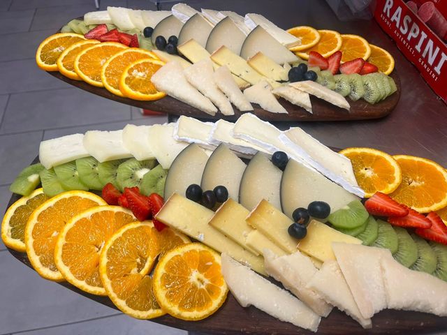 Tagliere assortiti di formaggi e frutta con fette d'arancia, uva e cracker su taglieri.