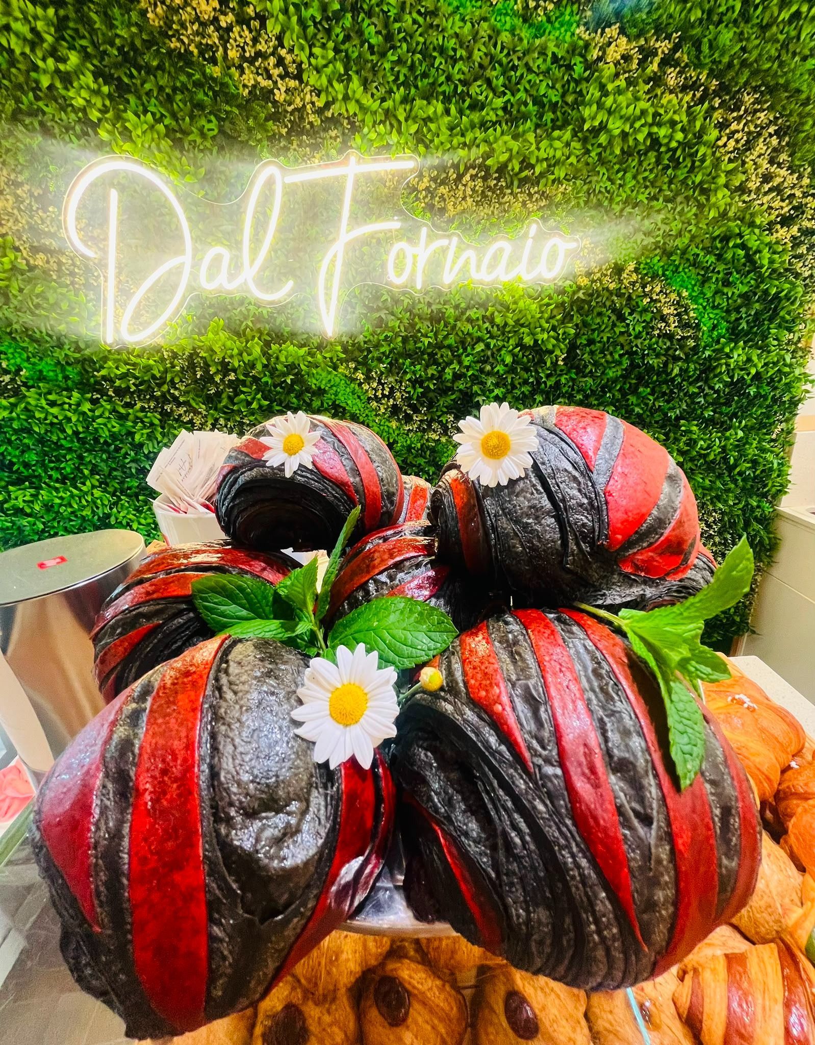 Composizione floreale colorata per dessert con margherite bianche sotto un'insegna luminosa con la scritta "Doll Farm".