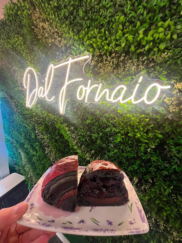 Due fette di dessert al cioccolato su un piatto davanti a una parete verde con un'insegna luminosa Del Formato