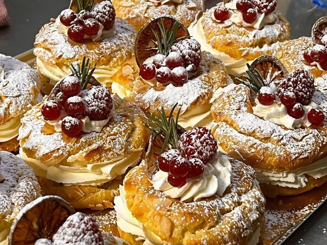Pasticcini con zucchero a velo, panna montata e frutti rossi, disposti su un vassoio.