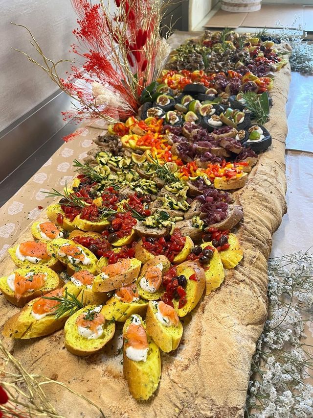 Sushi roll colorati disposti in file su un tavolo di legno, guarniti con vari tipi di decorazioni e salse.