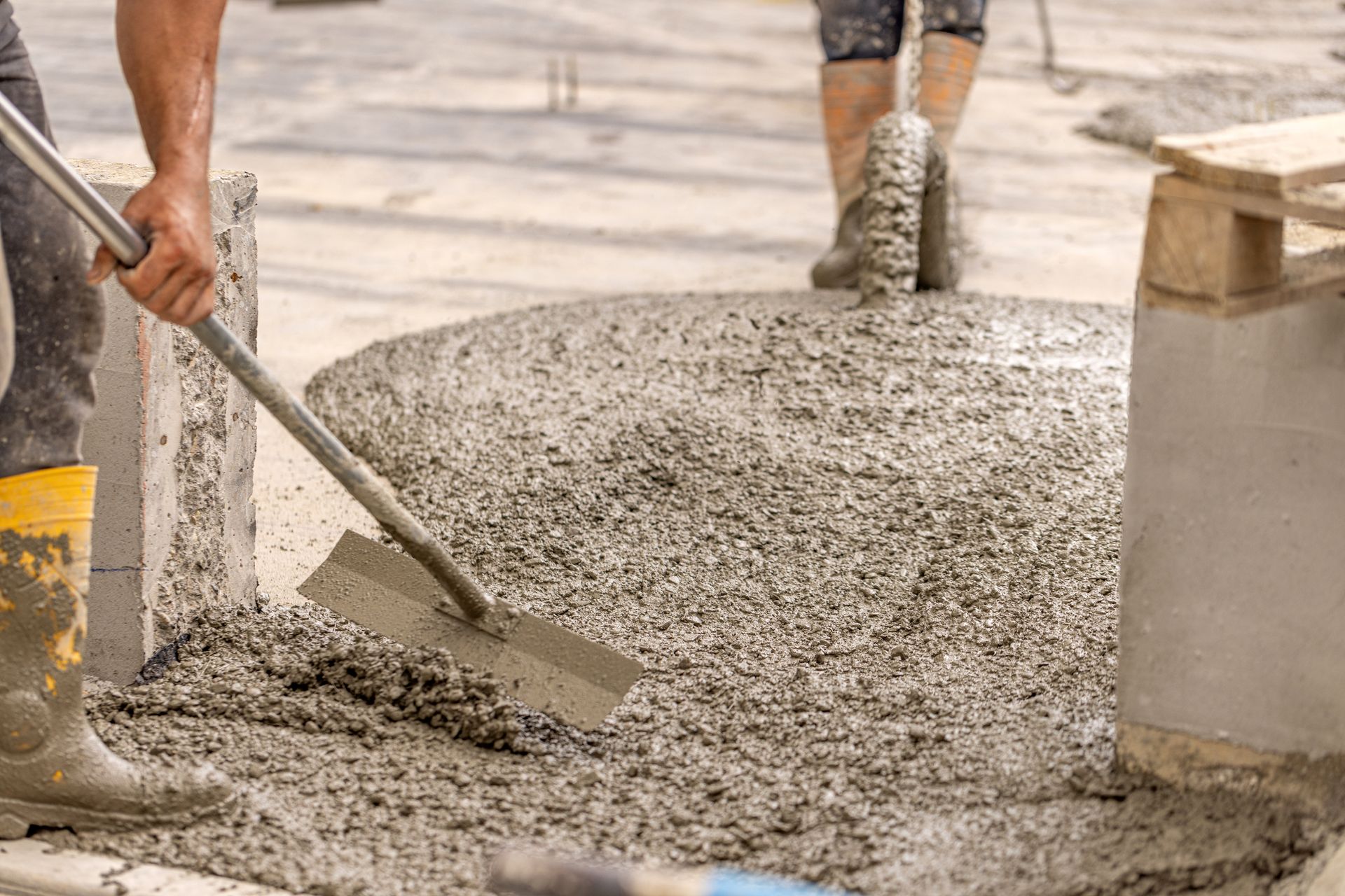 Workers pouring and smoothing wet concrete at a construction site Workers pouring and smoothing wet concrete at a construction site