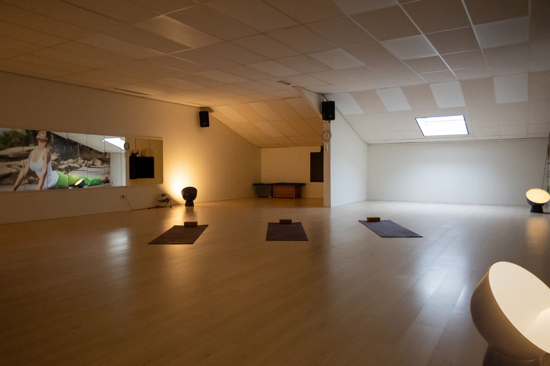 Voor een raam zit een groep vrouwen op yogamatten.
