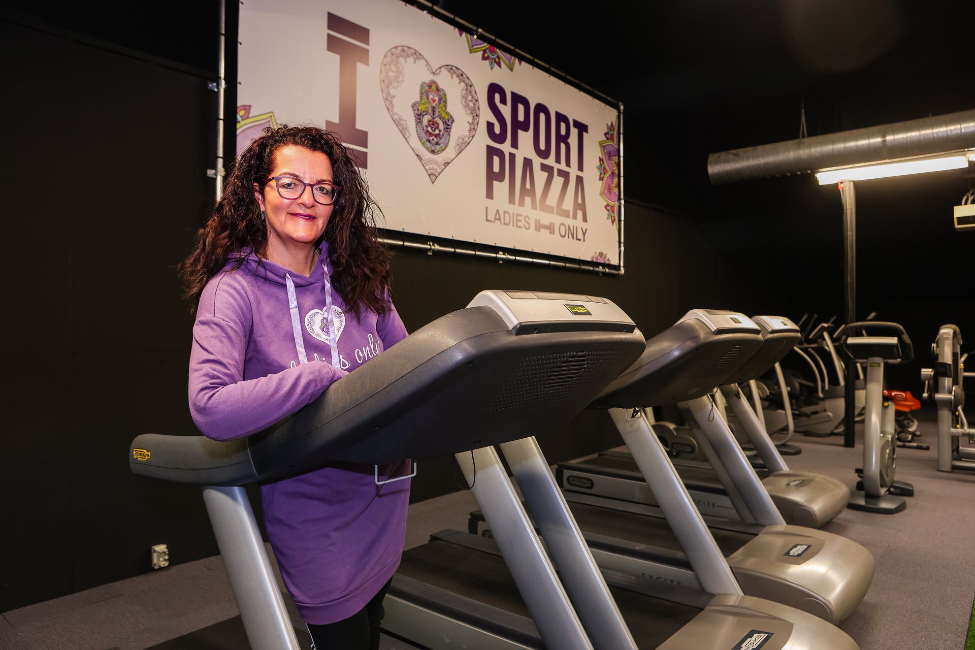 Een vrouw staat op een loopband in een sportschool.