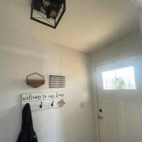 White entryway with wall decor, a coat on hooks, and a front door with a small window.