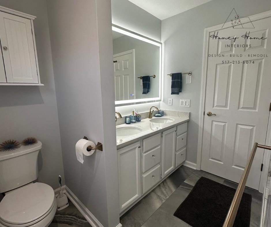 Small bathroom with toilet, vanity sink, mirror, and shower curtain in gray and white tones