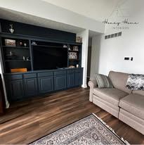 Modern living room with dark built-in cabinet, beige sofa, and patterned rug on wood floors
