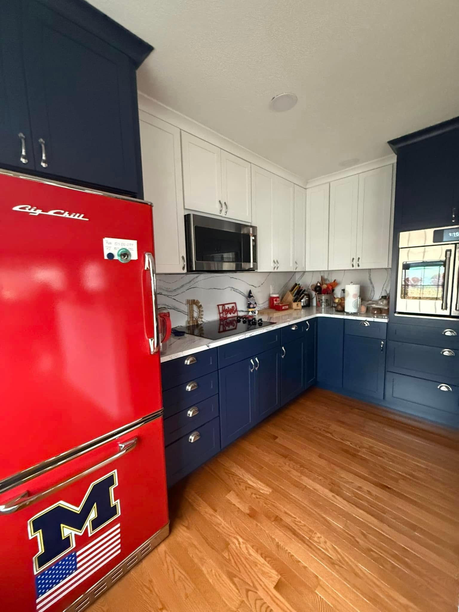 Kitchen with bright red retro refrigerator, blue cabinets, white counters, and wood floor