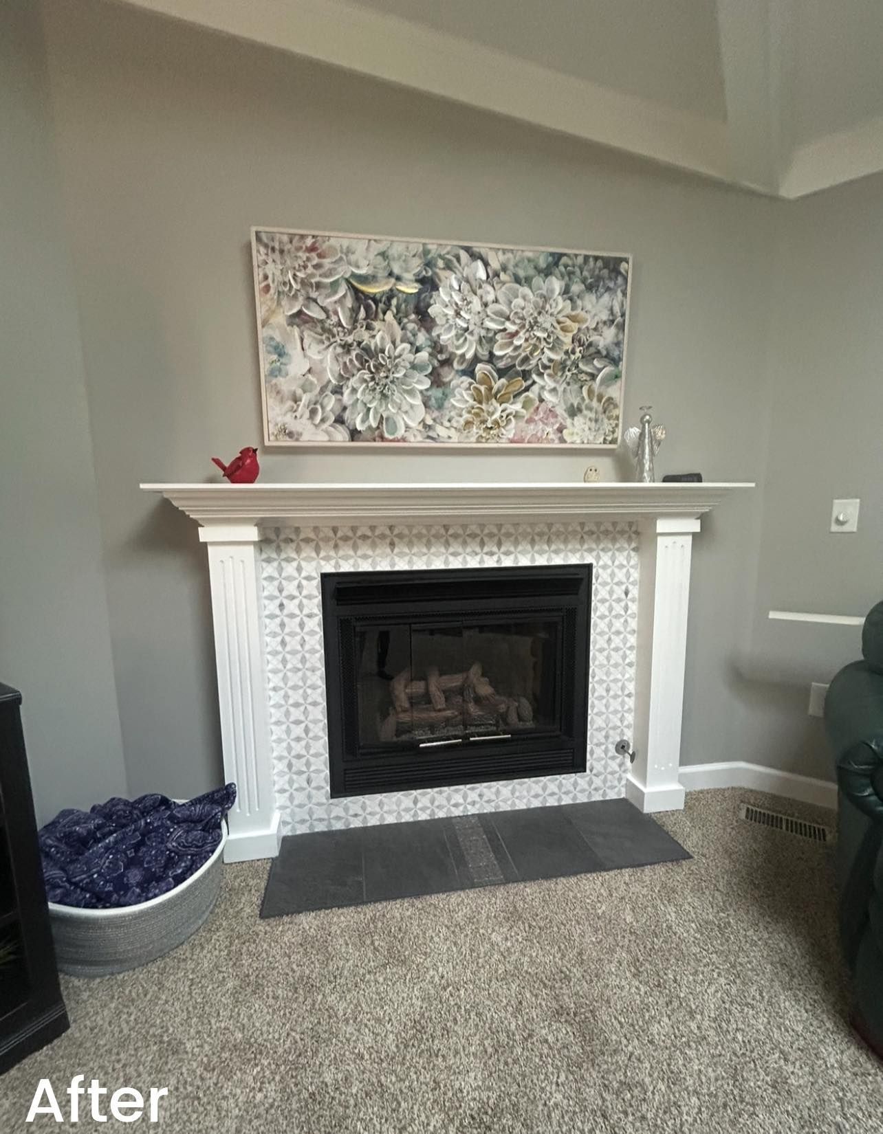 Living room fireplace with white mantel, abstract art above, and gray carpet.