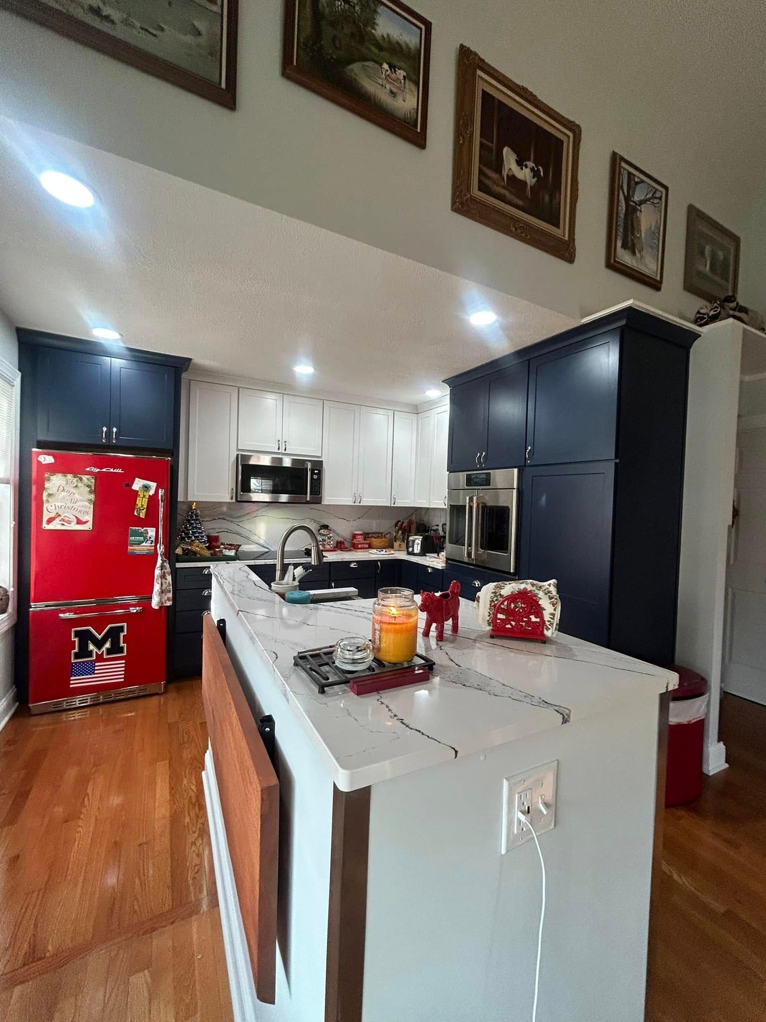 Modern kitchen with white island, black cabinets, and red refrigerator, viewed from the doorway