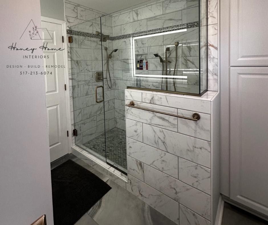 Modern bathroom with glass shower, white marble tile, and vanity cabinet mirror