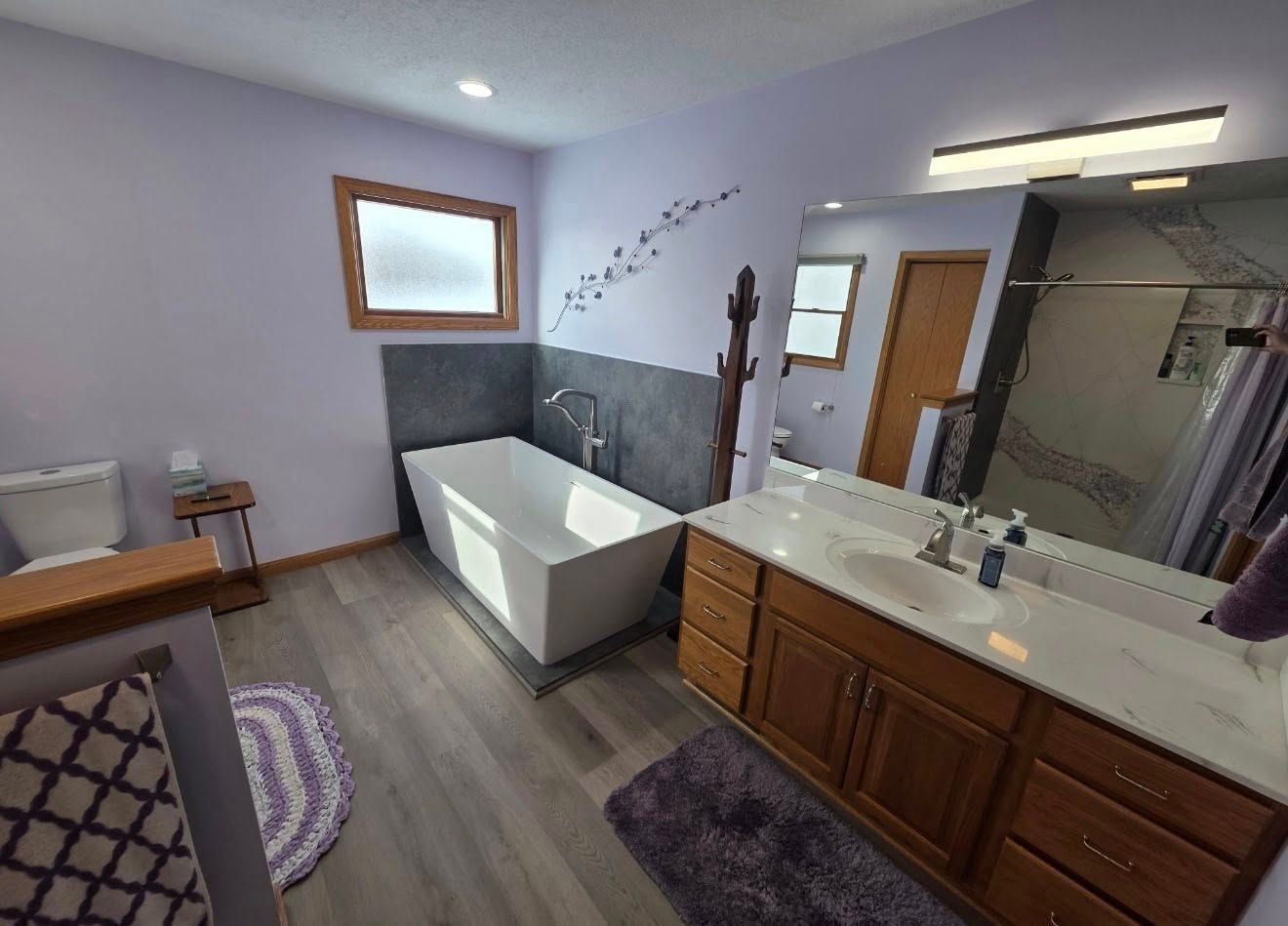 Bathroom with bathtub, double sink vanity, mirror, and window, in neutral gray and wood tones