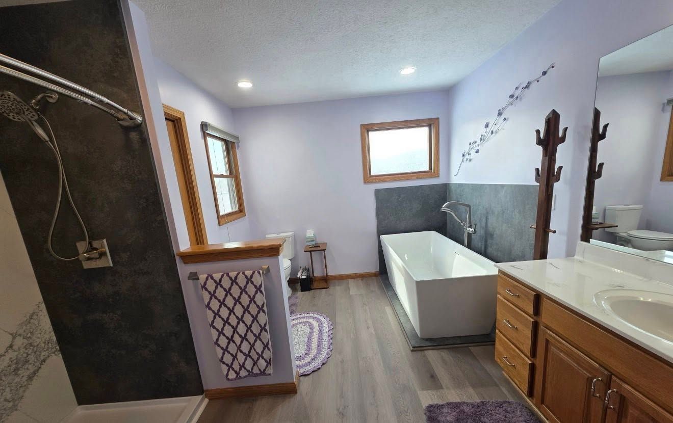Modern bathroom with clawfoot tub, double vanity, shower, and white walls with gray tile.
