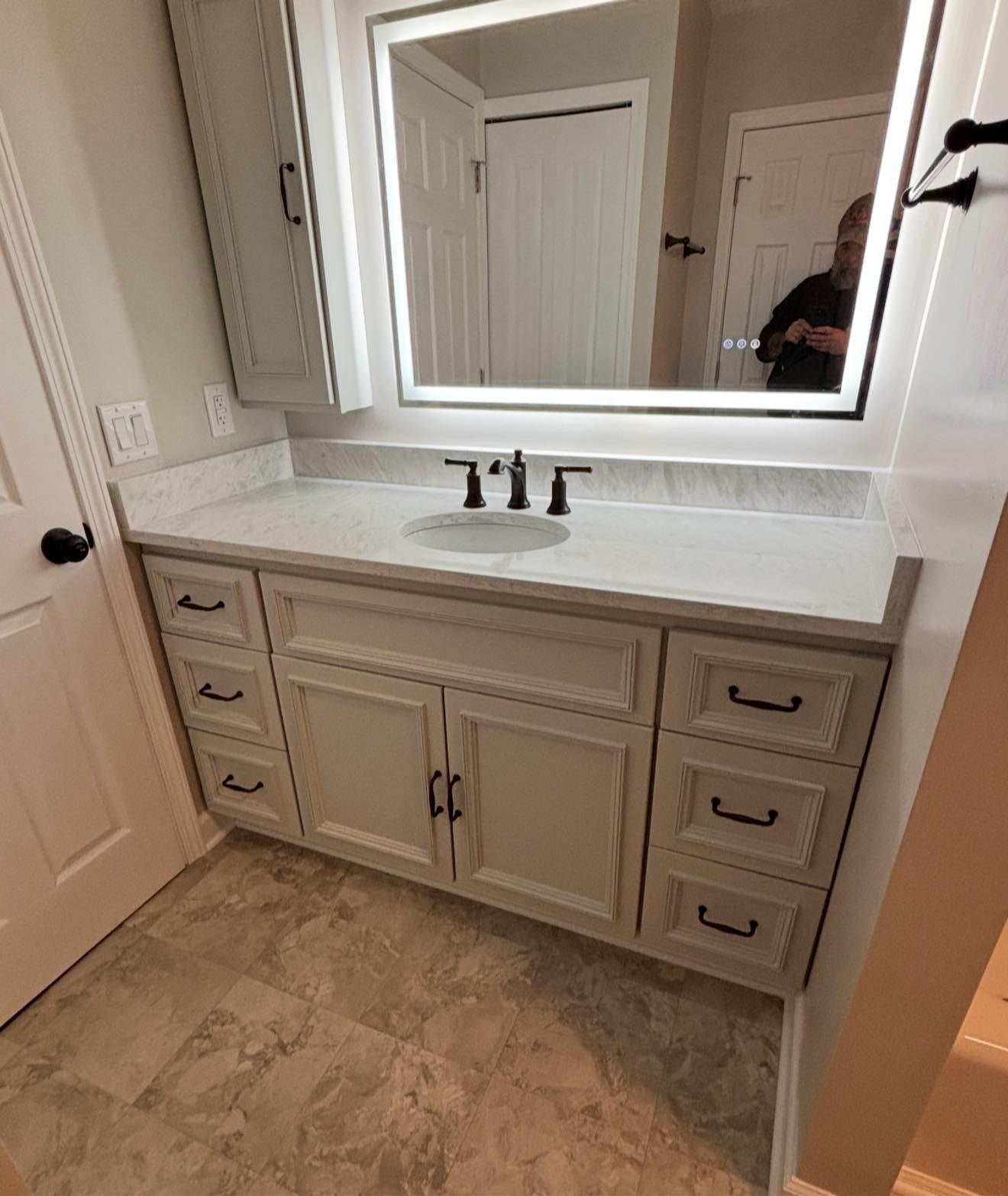 White bathroom vanity with double sinks, large mirror, and beige tile floor.
