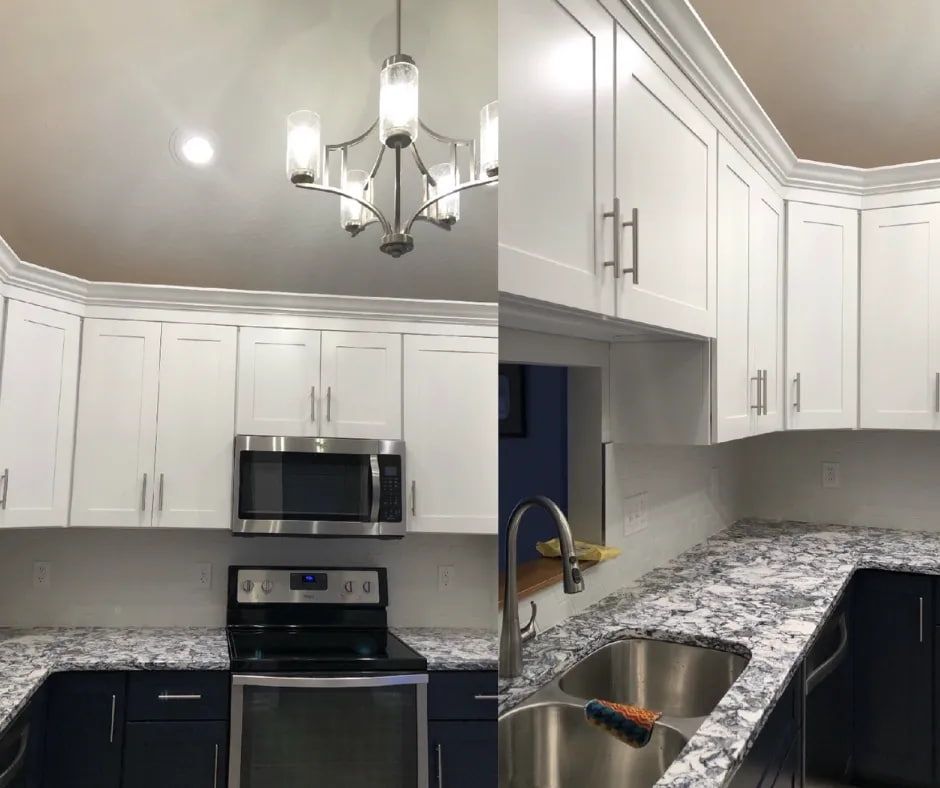 White and navy kitchen with granite countertops, stainless steel appliances, and a chandelier.