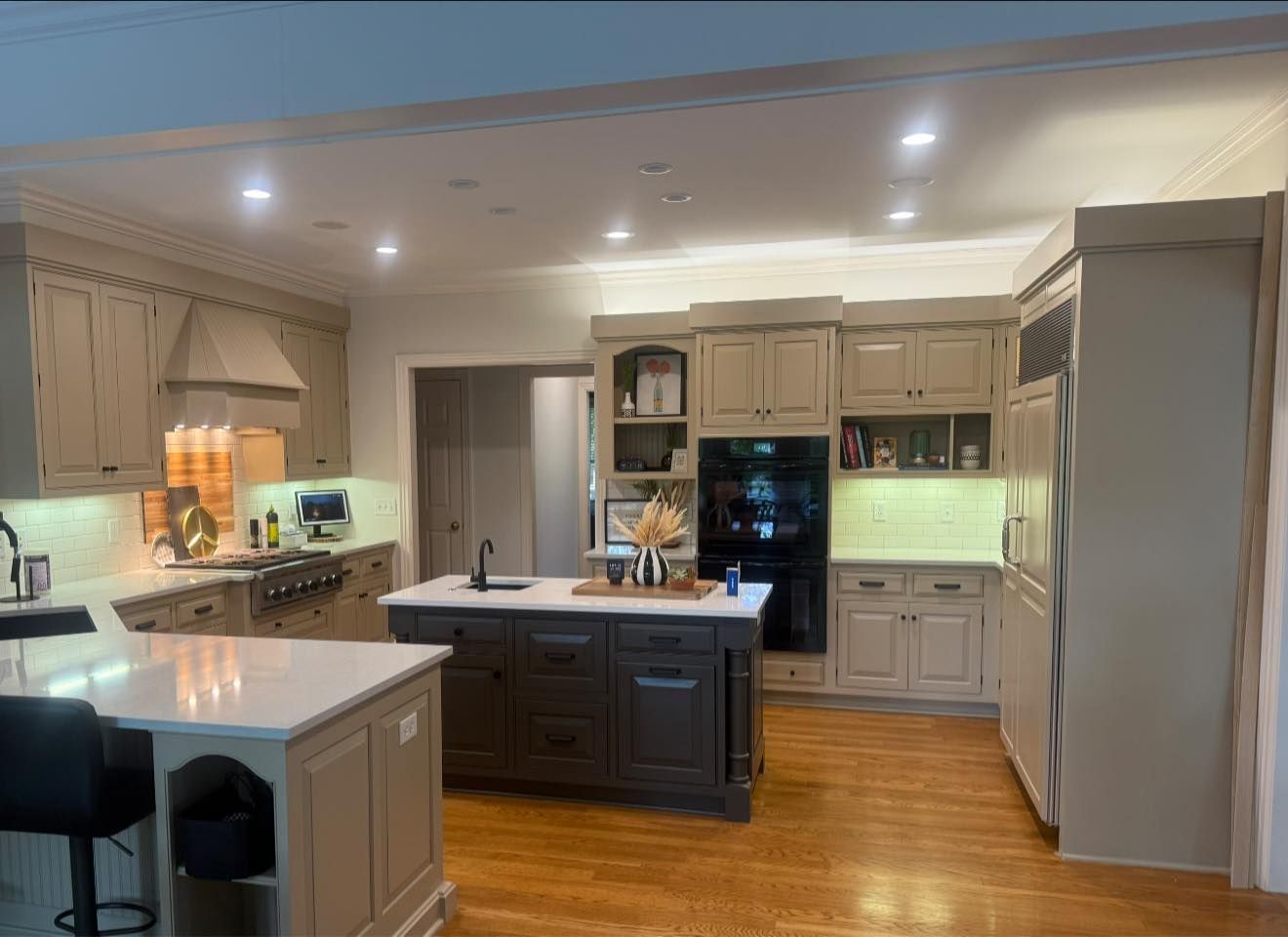 Bright modern kitchen with white cabinets, island, hardwood floors, and recessed ceiling lights