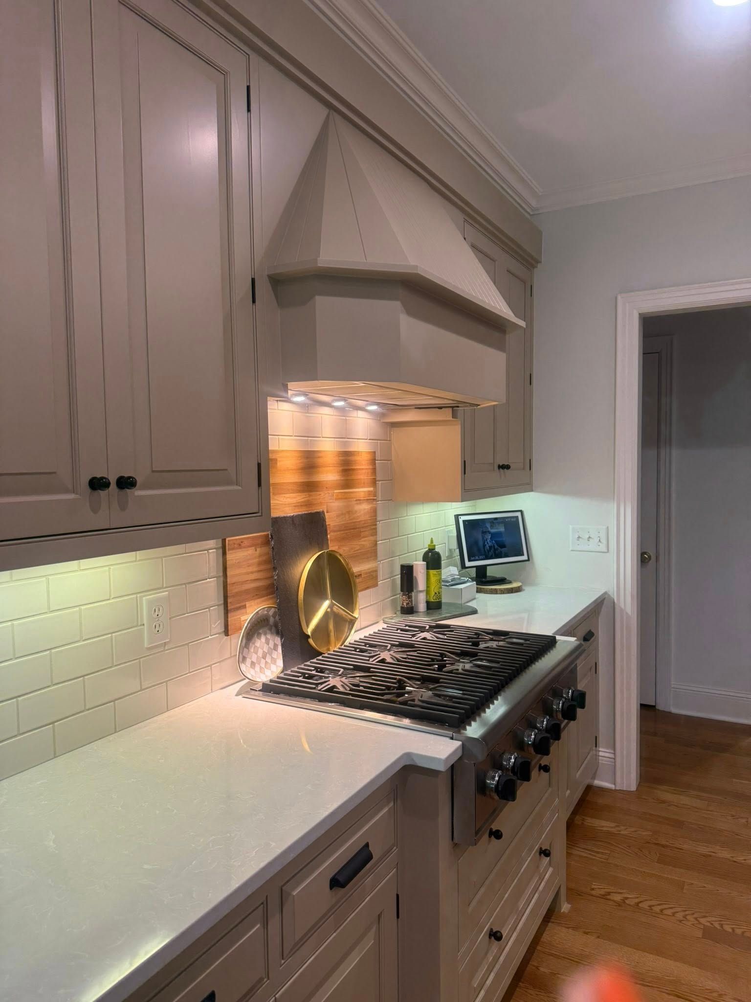 Bright modern kitchen with cream cabinets, white tile backsplash, and a stainless range under a hood.