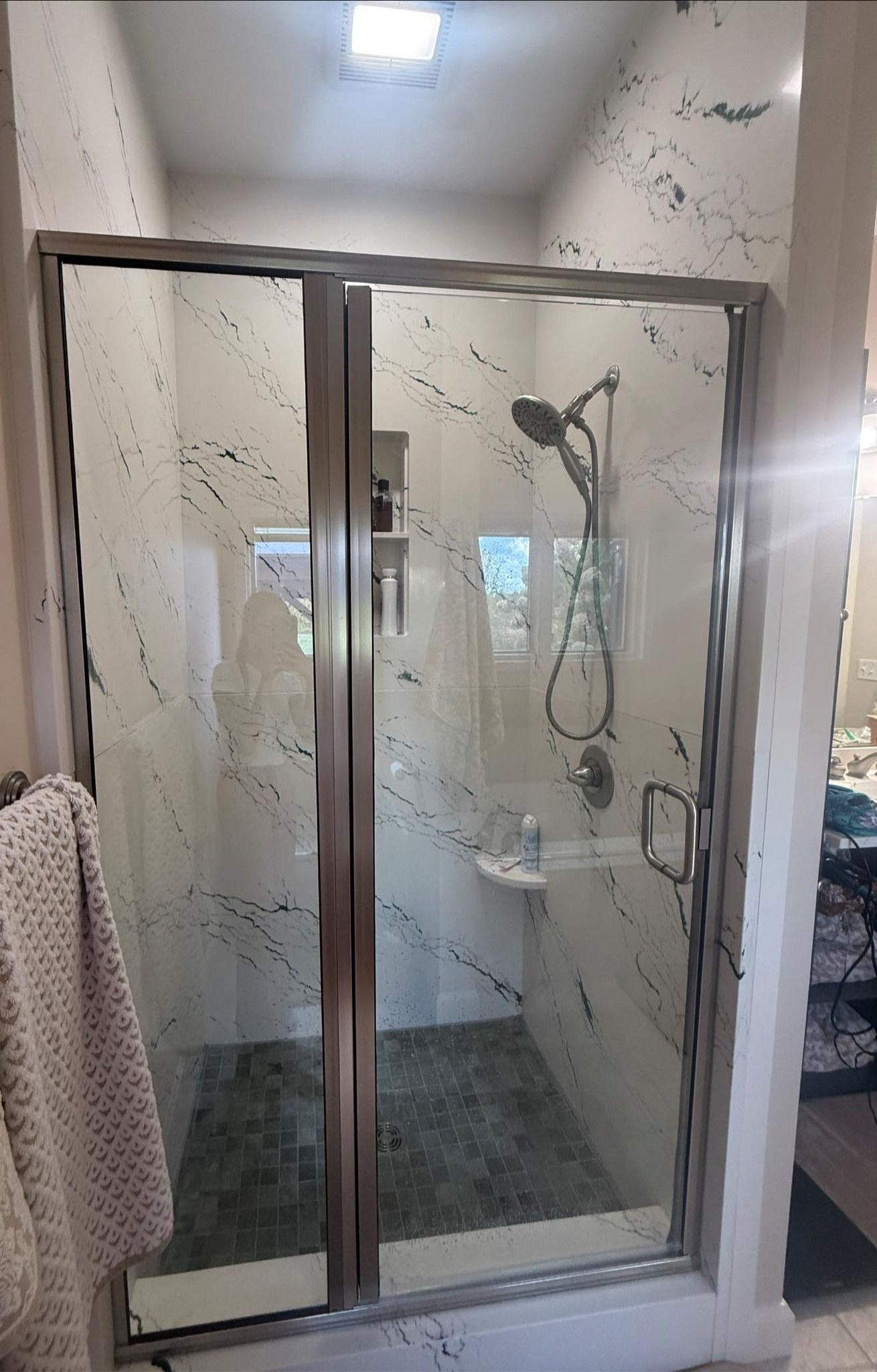 Glass shower enclosure in a bathroom with a handheld showerhead and frosted, textured panels.