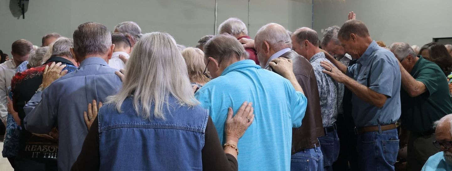 Group praying together and placing hands on backs