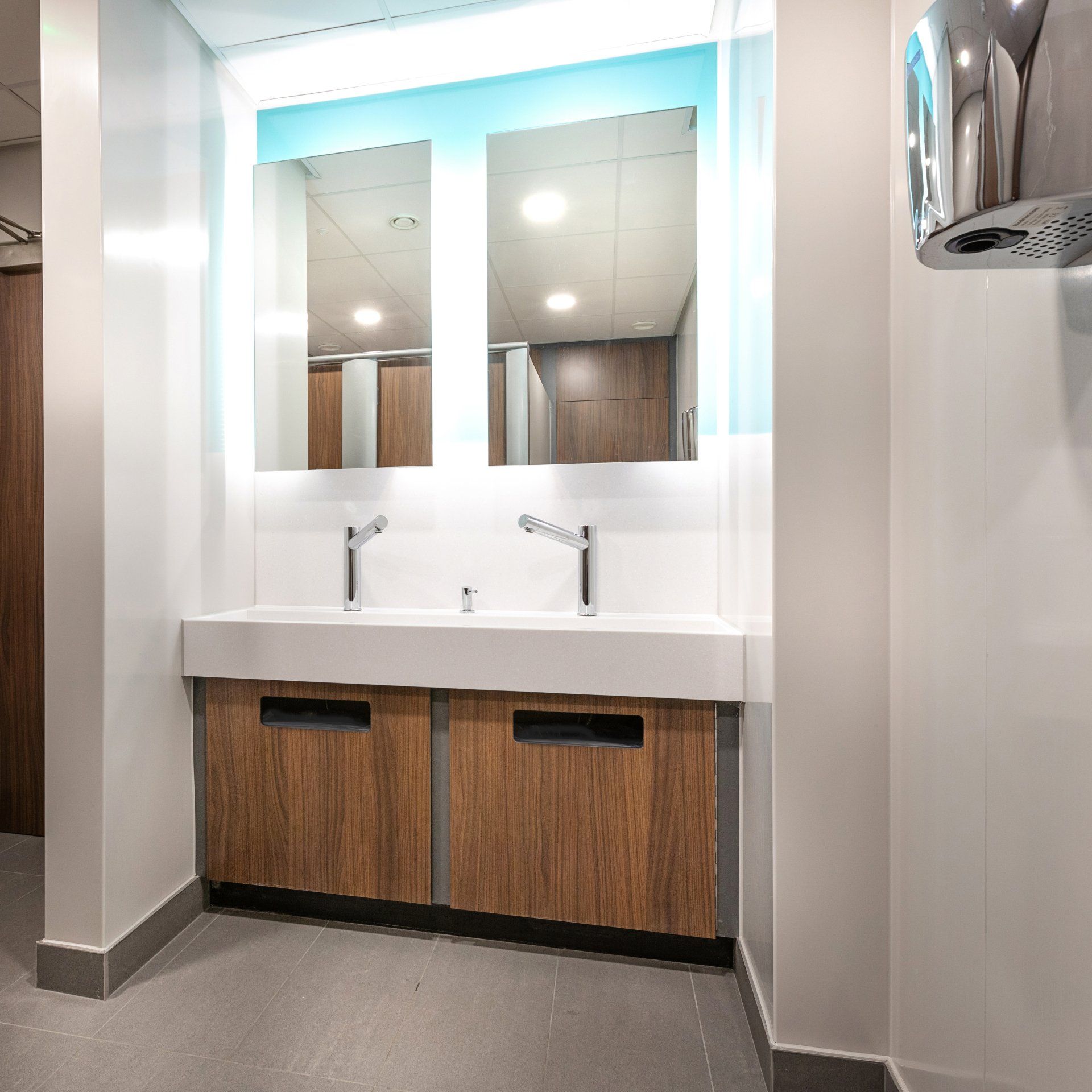 A bathroom with two sinks and a hand dryer