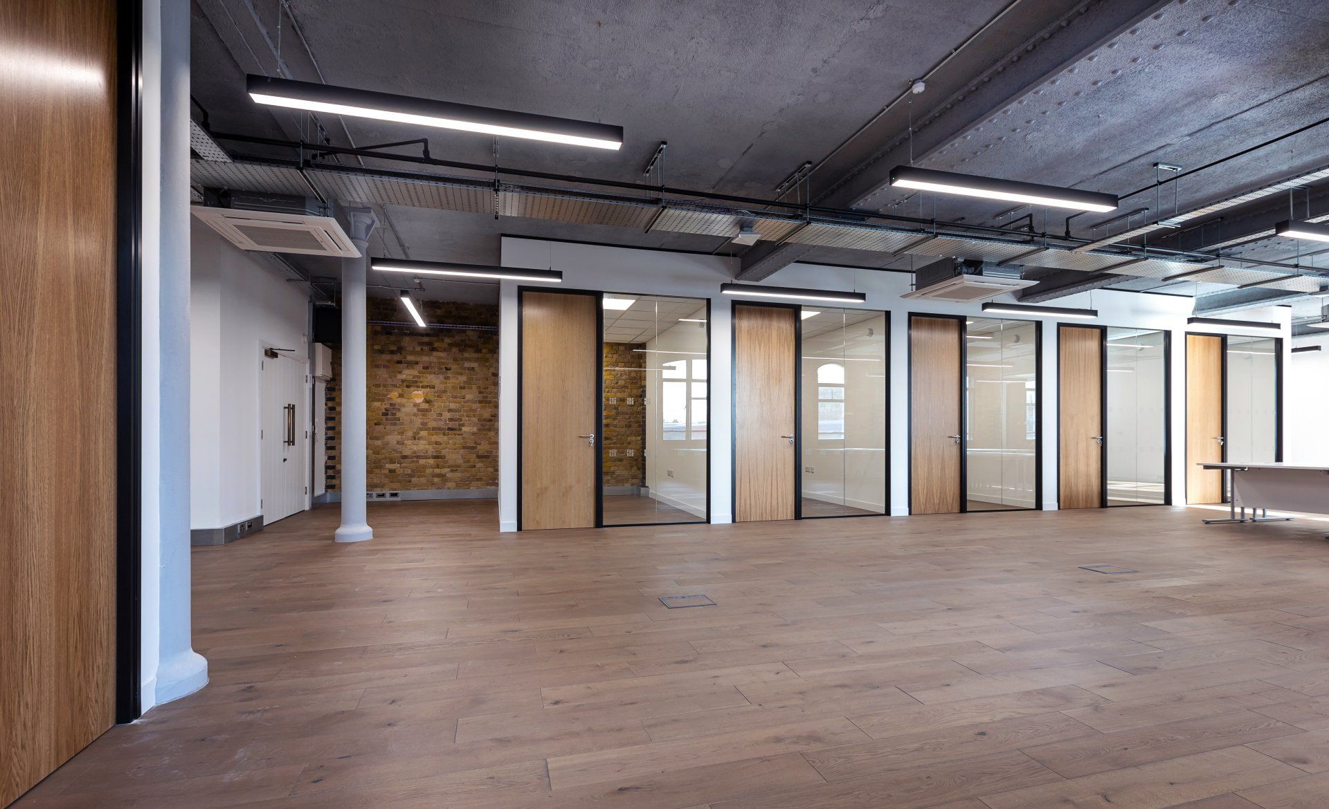 A large empty room with wooden floors and glass doors.