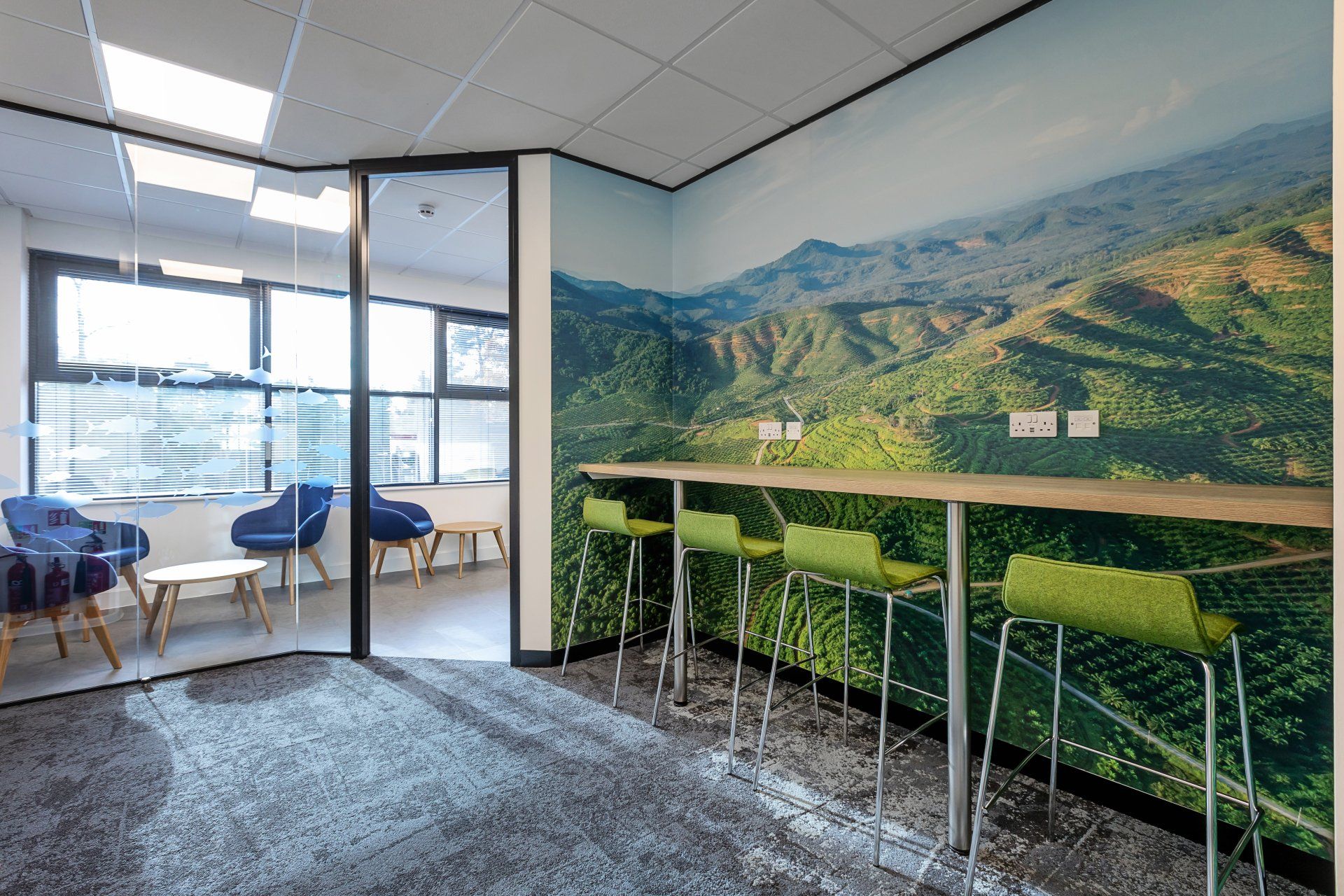 A room with a table and chairs and a picture of a mountain on the wall.
