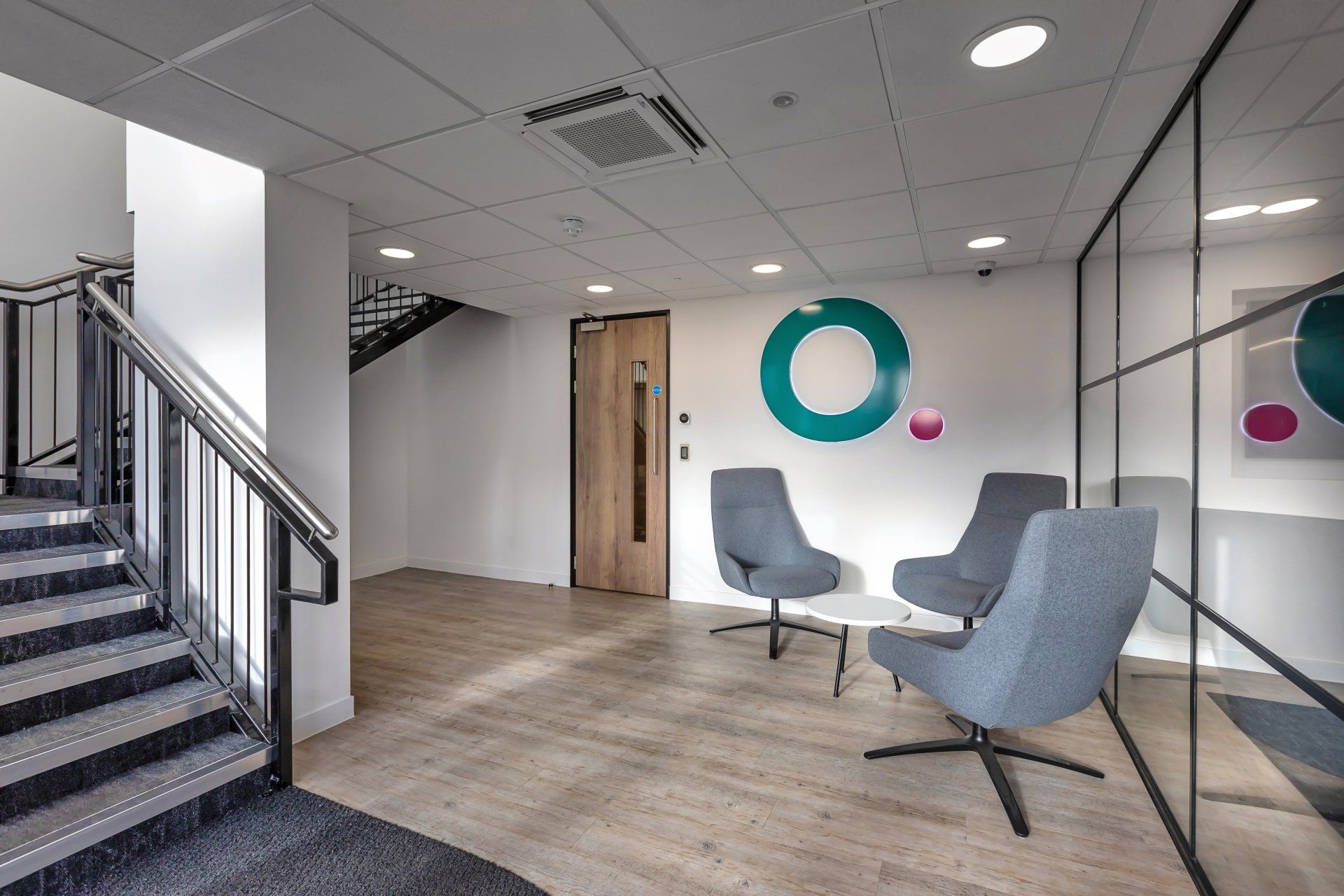 A waiting room with chairs and stairs in a building.