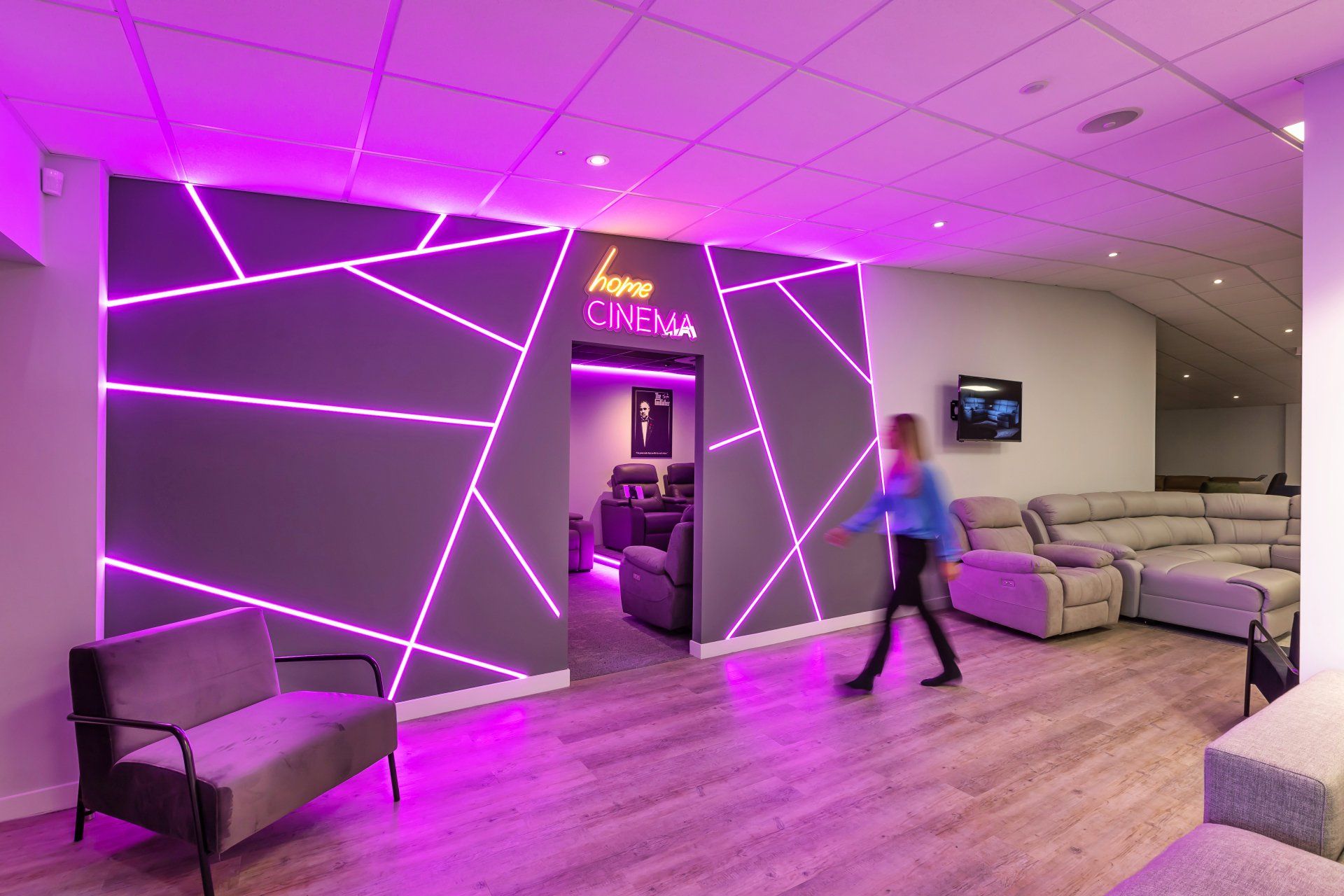 A woman is walking through a lobby with purple lights on the walls.