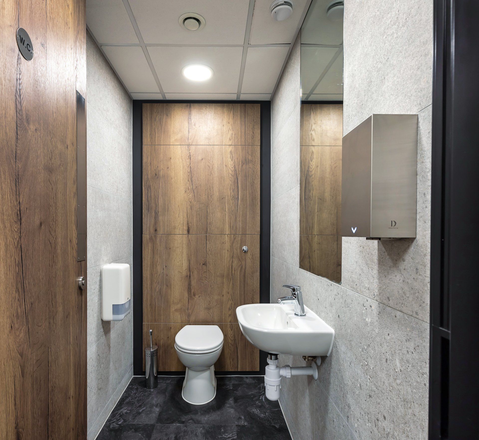 A bathroom with a toilet , sink and mirror.