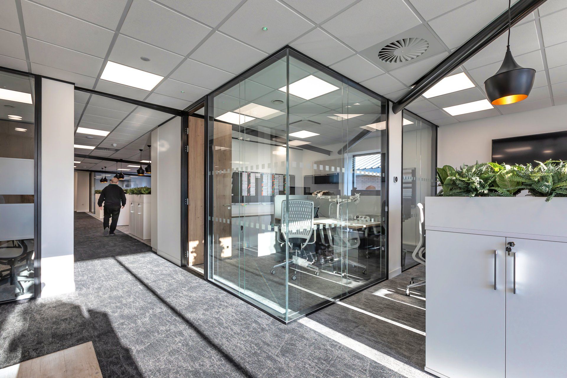 A man is walking down a hallway in an office building.