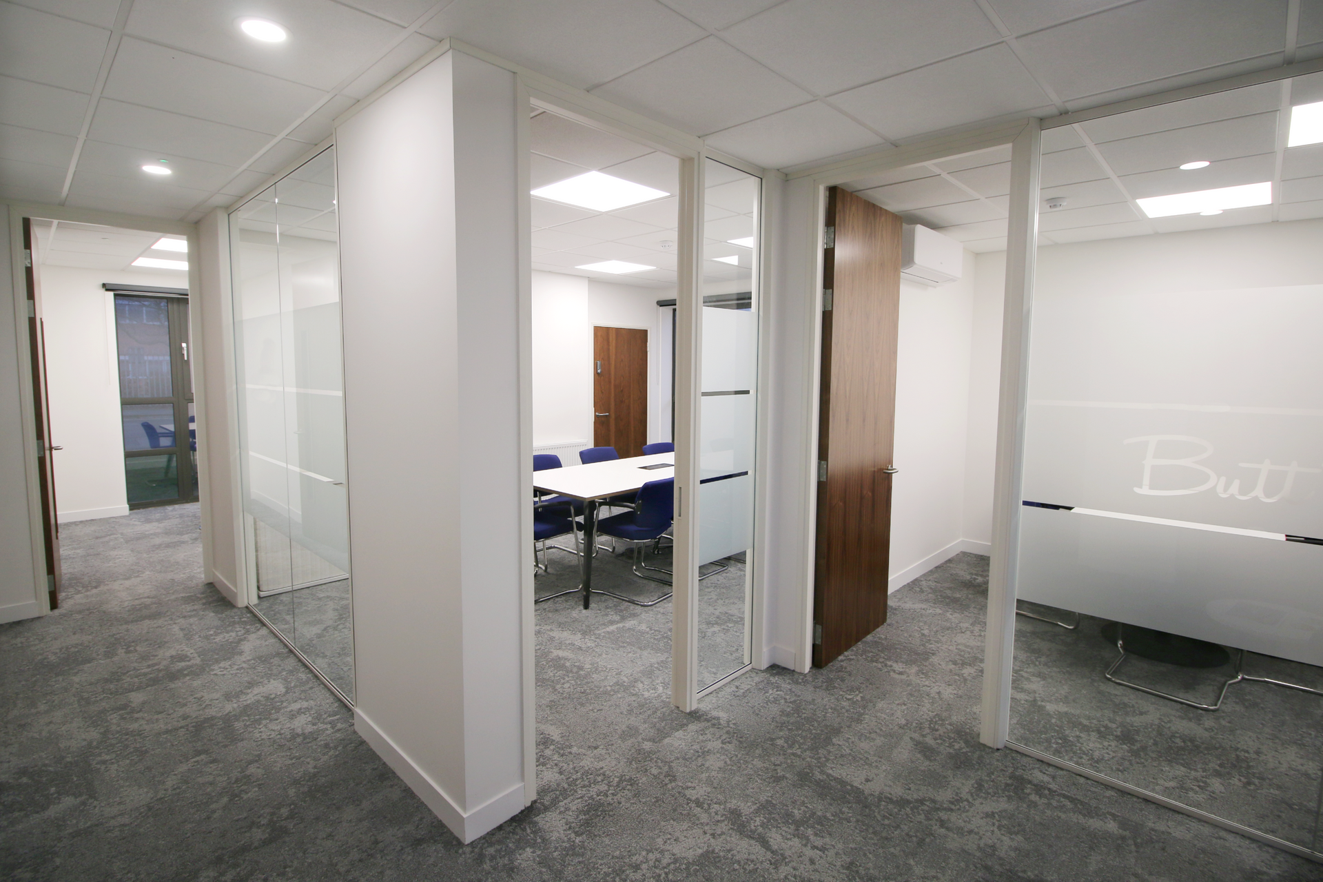 A hallway leading to a conference room with a table and chairs.
