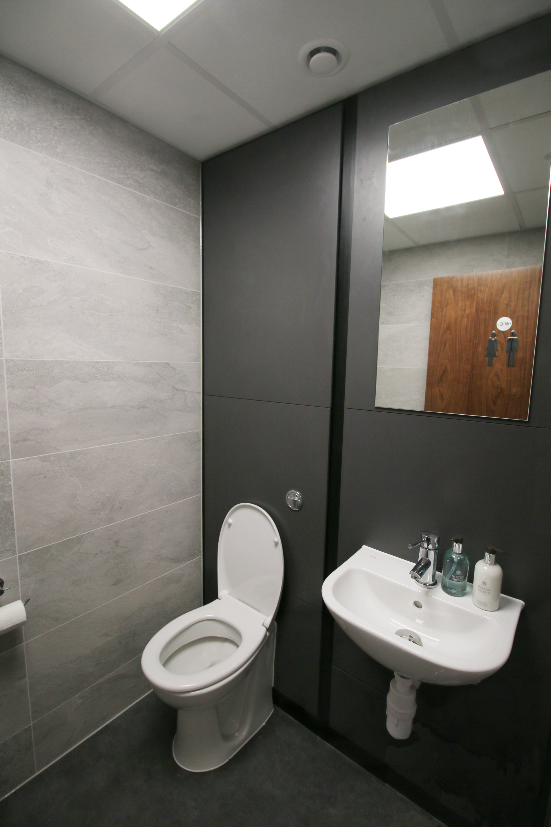 A bathroom with a toilet , sink and mirror.