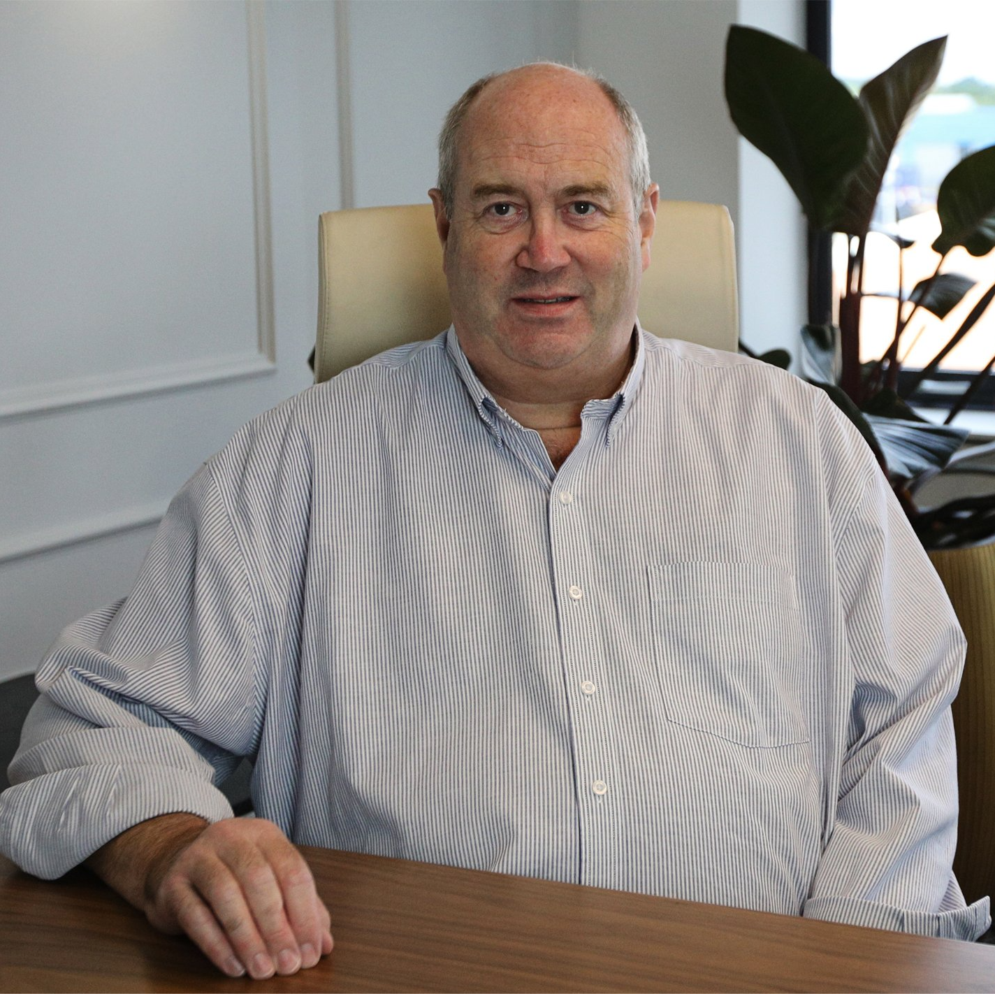 A man in a striped shirt sits at a desk
