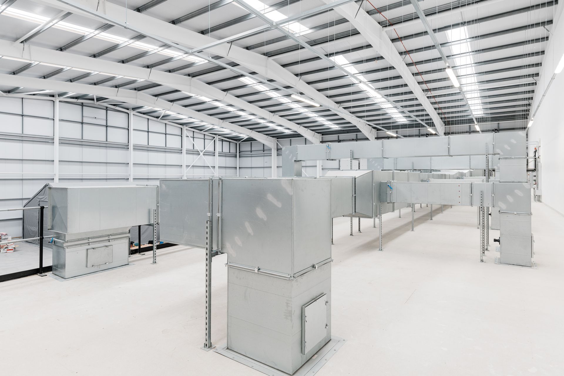 An empty warehouse with a lot of pipes going through it.