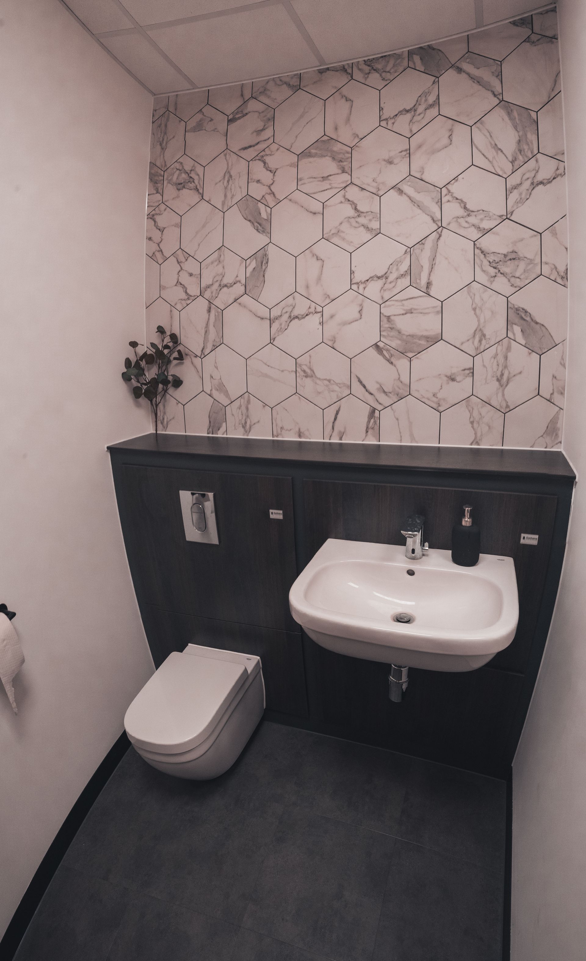 A bathroom with a toilet , sink and toilet paper