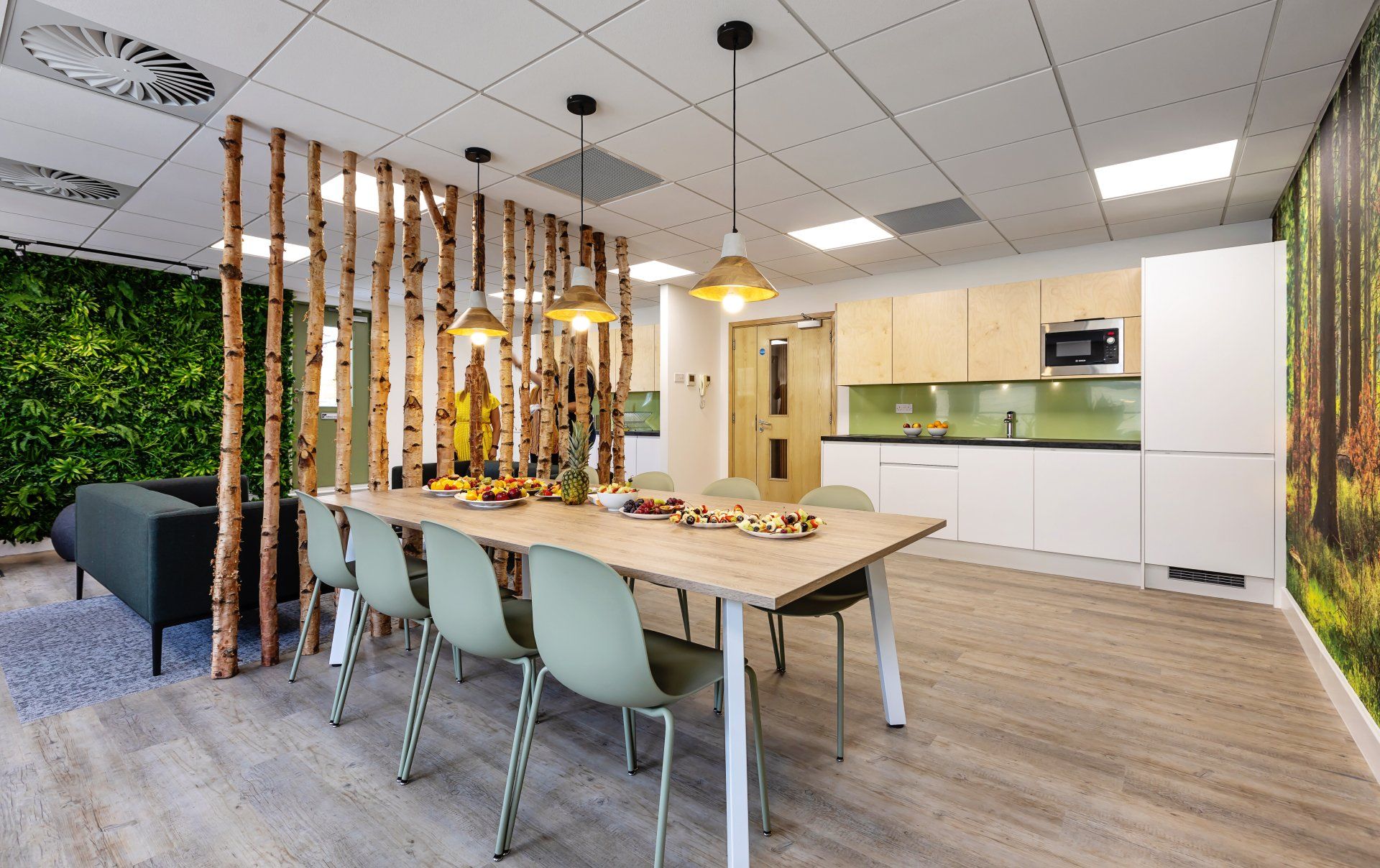 a dining room with a long table and chairs and a kitchen .
