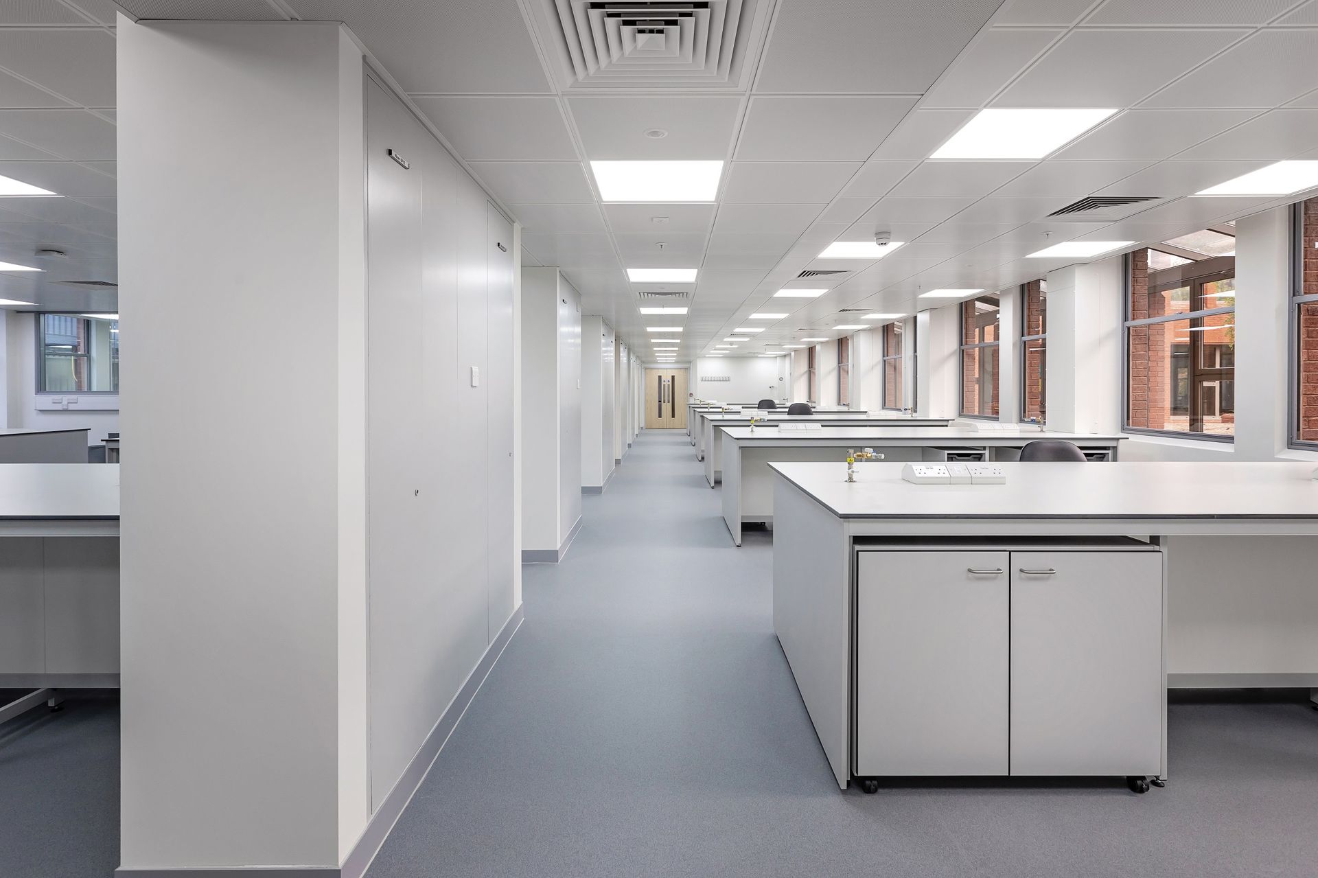 A long hallway in an office building with white desks and cabinets.