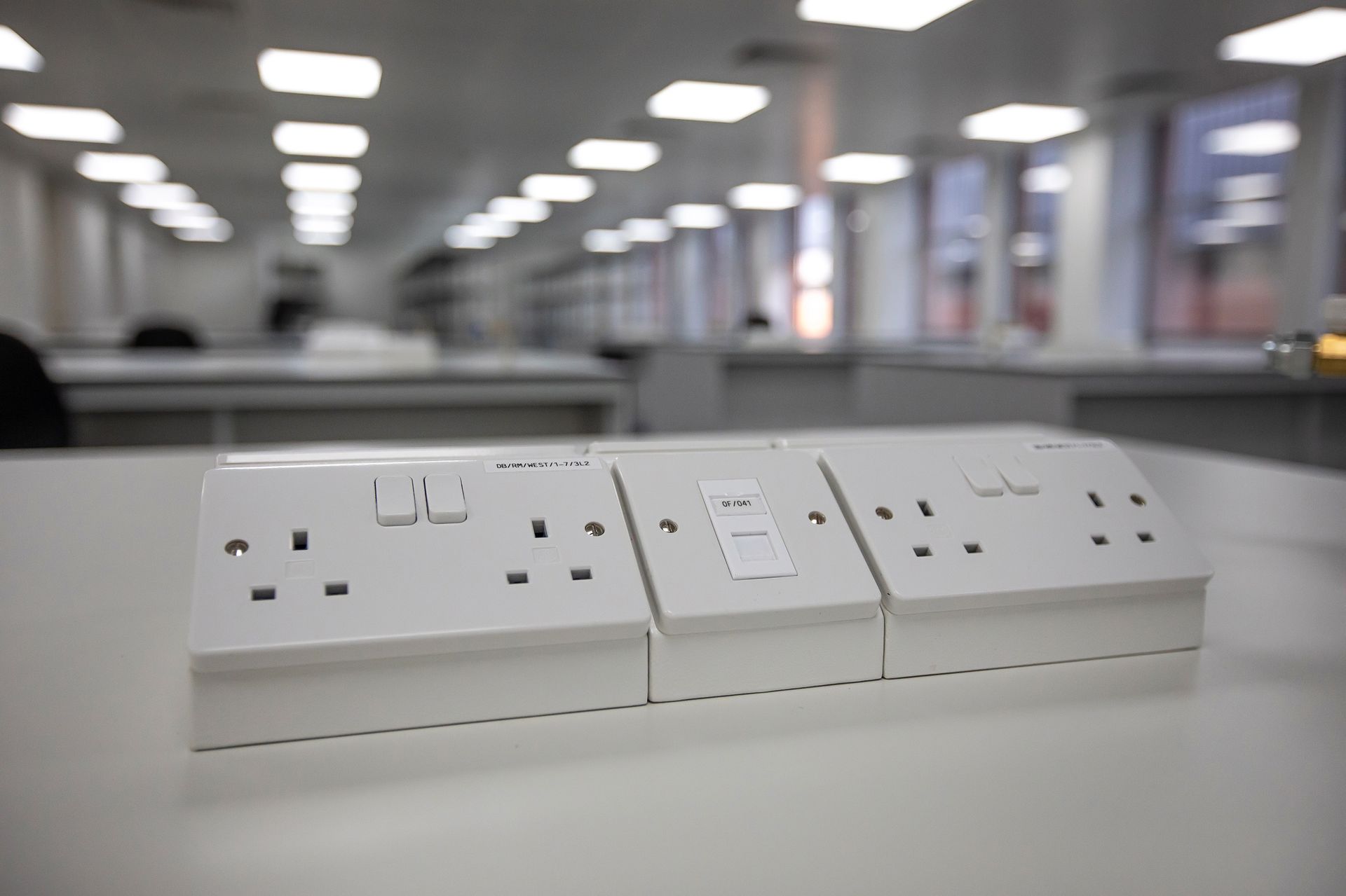 A row of white electrical outlets on a desk in an office