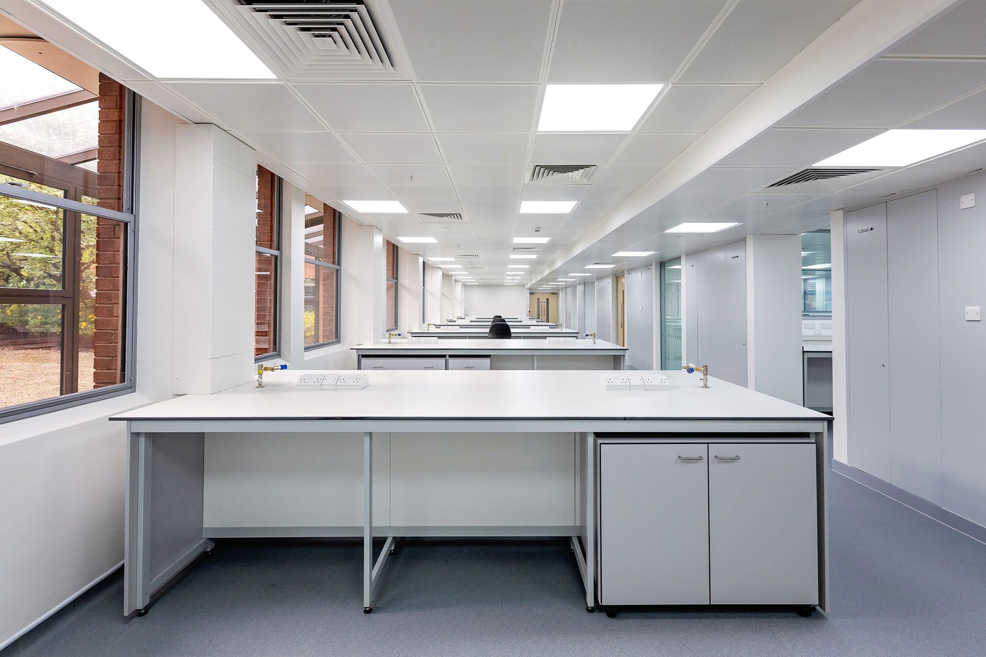 A large empty office with a lot of desks and cabinets.