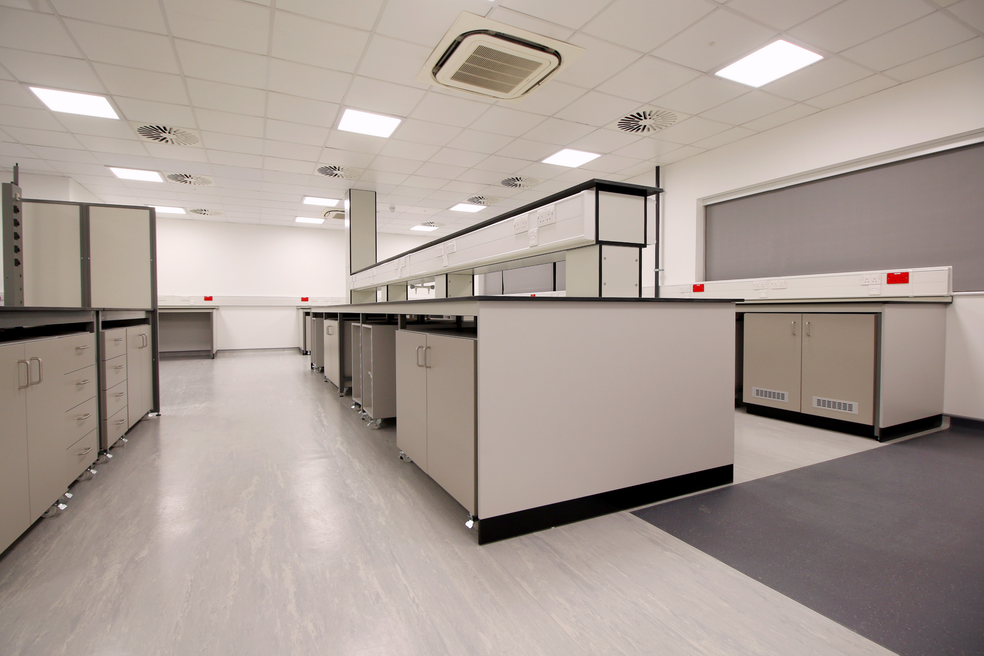 A large empty laboratory with a lot of cabinets and counters.